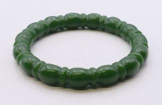 A dark green ribbed jade bangle. 6 cm inner diameter.