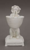 A Victorian porcelain model of a begging dog holding a basket in its mouth. 19 cm high.