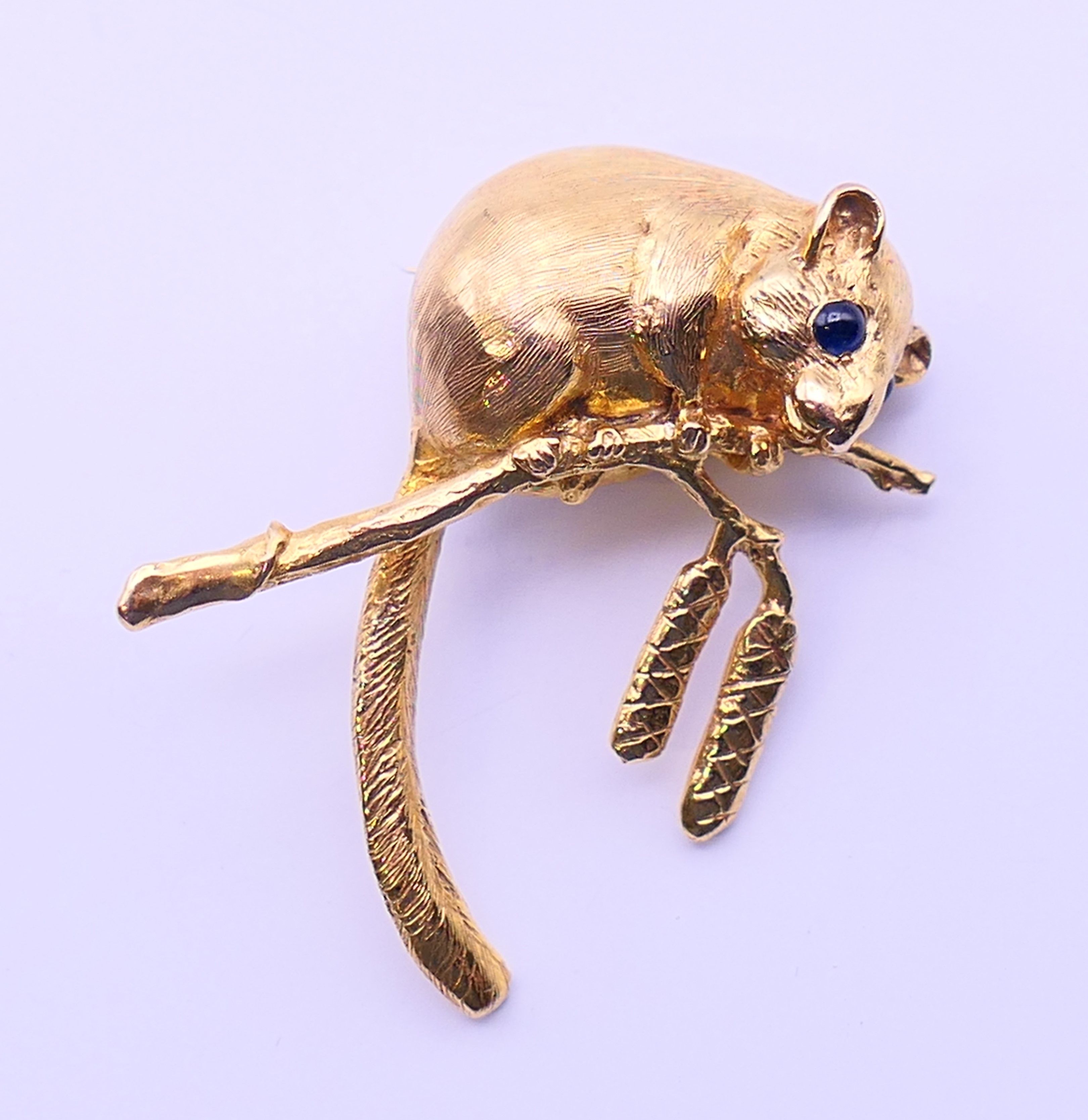 A gold dormouse form brooch with sapphire set eyes. 4 cm high. 13.9 grammes.