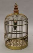 A brass birdcage enclosing a model of a parrot. 60 cm high.