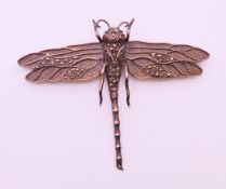 A Silver dragonfly brooch with garnet set eyes. 8.5 cm x 7 cm.