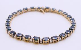 A 14 K gold, diamond and sapphire line bracelet. 18 cm long.