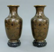 A pair of black cloisonne vases on wooden stands. 24.5 cm high.