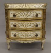 A gilt and white painted serpentine chest of drawers. 76 cm wide.