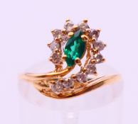 An unmarked probably 18 ct gold emerald and diamond ring. Ring size J.