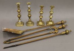 A set of three brass fire irons and two pairs of brass candlesticks. The largest sticks 25 cm high.