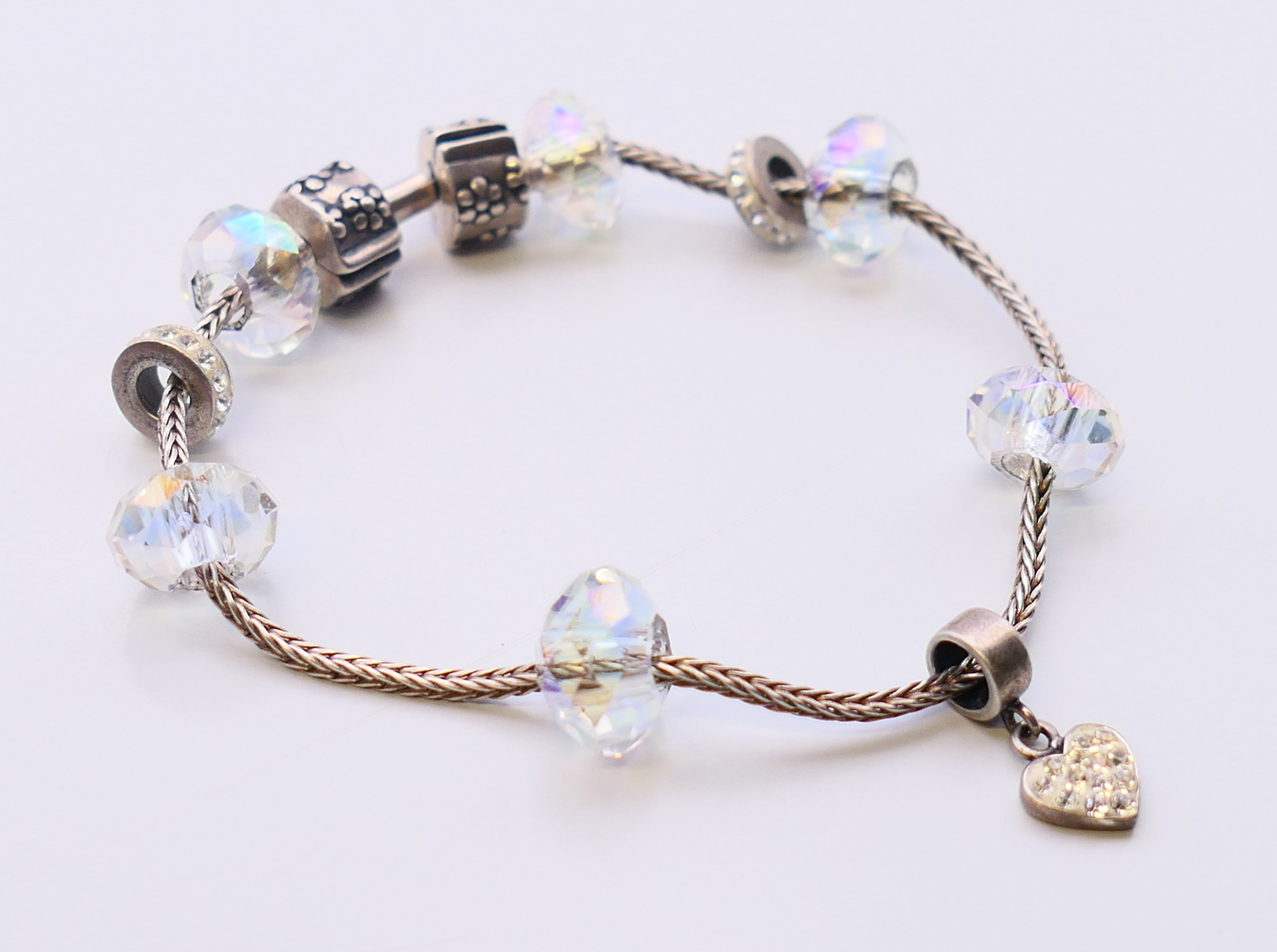A silver bracelet with silver and bead charms. 17 cm long.