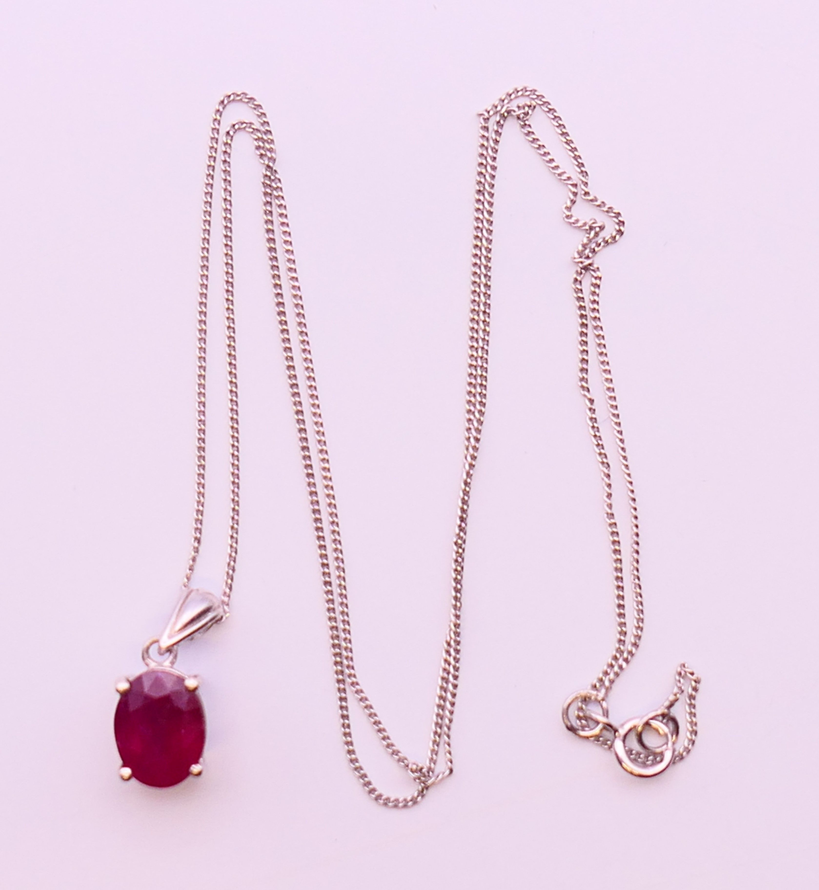 A silver ruby pendant on chain. Pendant 0.75 cm high, chain 45 cm long.