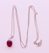 A silver ruby pendant on chain. Pendant 0.75 cm high, chain 45 cm long.