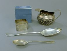 A boxed silver napkin ring, a silver cream jug and two silver spoons. The jug 9.5 cm long. 5.