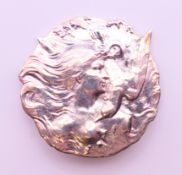 A silver Art Nouveau style female with a dove brooch. 4 cm diameter.