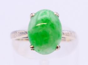 A 14K white gold single stone apple green jade ring. Ring size J.