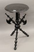A 19th century carved and ebonised tripod table, the base formed as three axes. 40.5 cm diameter.