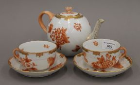 A Herend porcelain teapot and two cups and saucers. The teapot 20 cm long.