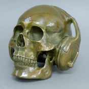 A bronze skull bearing headphones. 14 cm high.