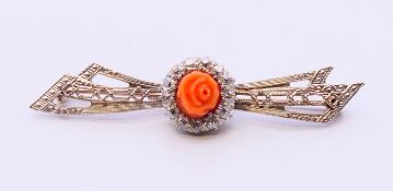 A 14 K gold, diamond and coral bow and flower form brooch. 5.5 cm long. 5 grammes total weight.