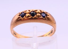 A 9 ct gold three-stone sapphire ring. Ring size N.