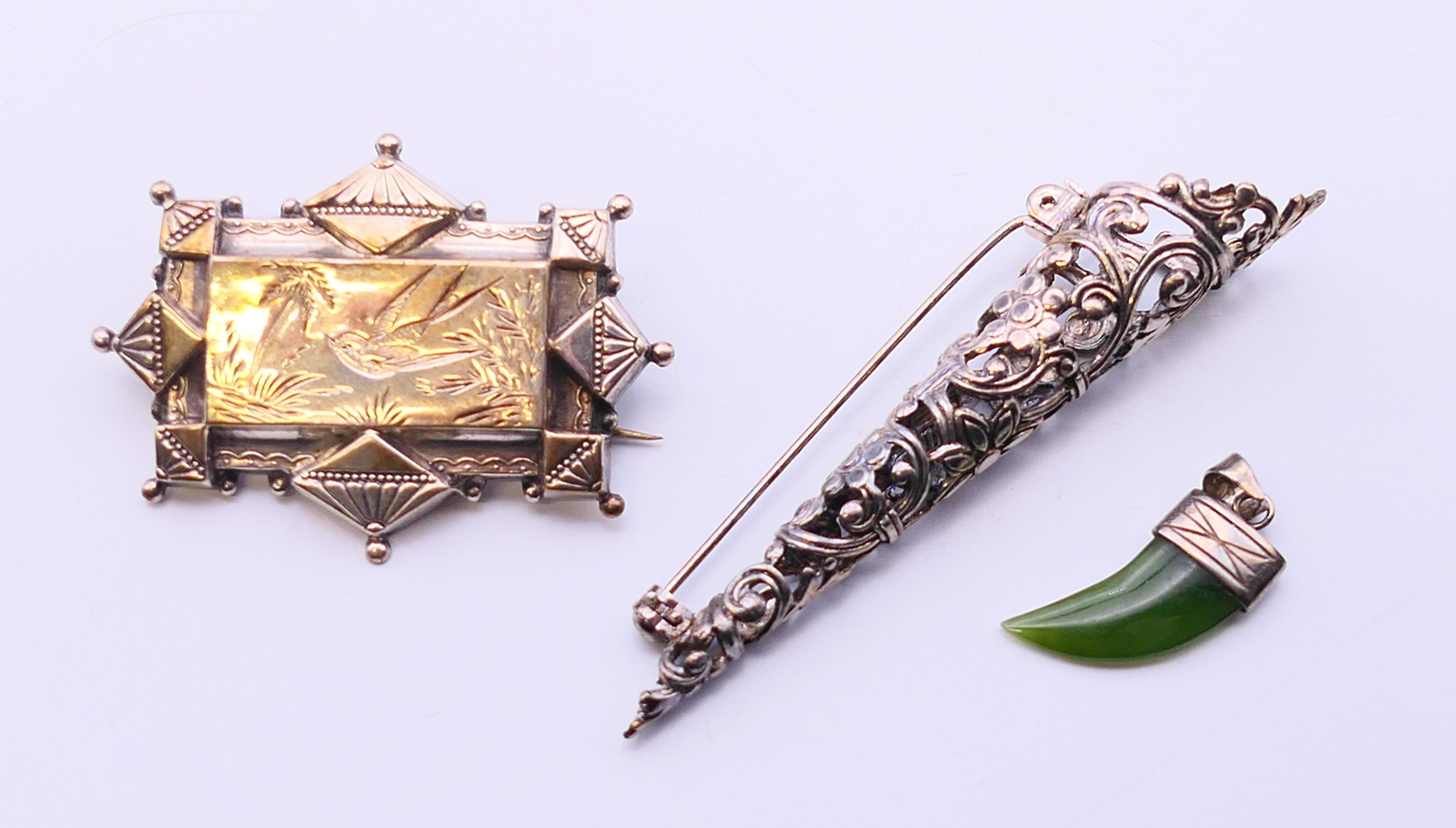 A Victorian silver brooch, a posy holder brooch and a silver and jade tiger tooth shaped pendant.