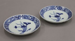 A pair of Chinese blue and white Wanli style saucers painted with a bouquet of lotus within a key