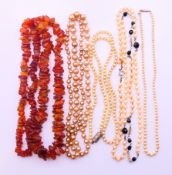 A natural amber necklace and four pearl necklaces. Amber necklace 66 cm long.