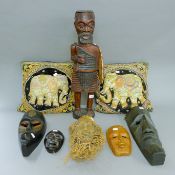 Seven tribal figures/masks and two cushions decorated with elephants. The largest 60 cm high.