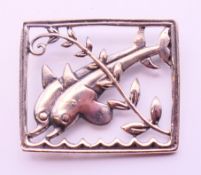 A silver square brooch with two dolphins. 3.5 x 3 cm.