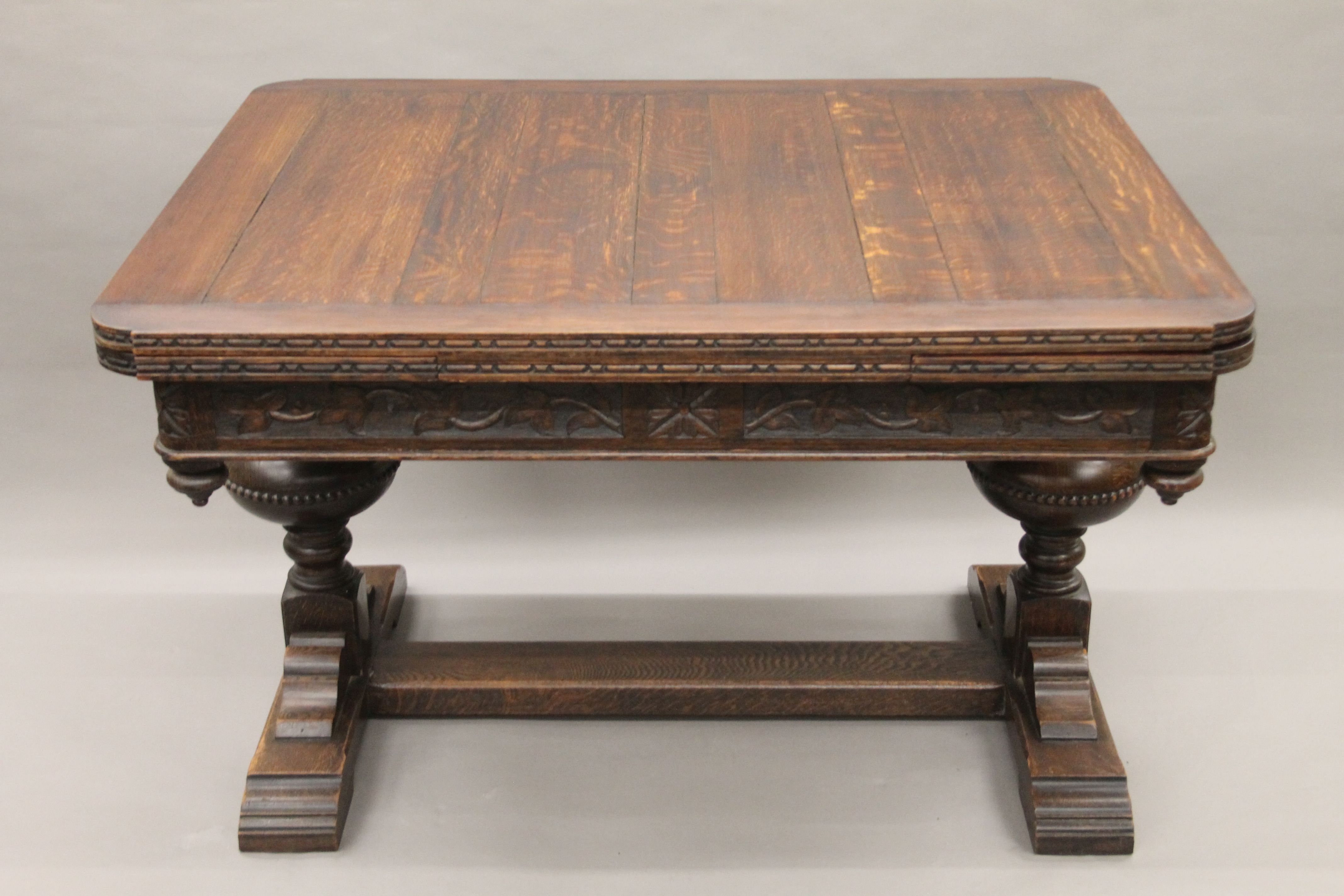 An early 20th century carved oak drawer leaf dining table. 193 cm long extended x 99 cm wide. - Image 6 of 6