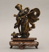 A Chinese tiger's eye hardstone carving of a maiden on a carved wood base. 18.5 cm high.