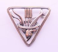 A silver brooch of triangular form with a dolphin and reeds to the centre. 3 cm high.