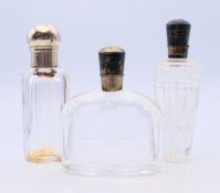 Three silver topped scent bottles. 9 cm high.