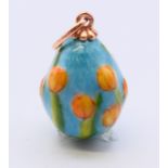 A 14 ct gold and enamel egg pendant decorated with tulips, bearing Russian marks. 2 cm high.