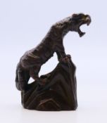 A bronze tiger standing on a rocky outcrop. 5 cm high.