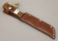 An army survival knife in a leather sheath. 33 cm long overall.