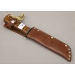 An army survival knife in a leather sheath. 33 cm long overall.