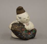 A 19th century ceramic netsuke formed as a boy with a fish. 6.5 cm high.