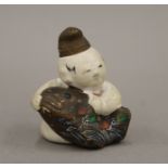 A 19th century ceramic netsuke formed as a boy with a fish. 6.5 cm high.