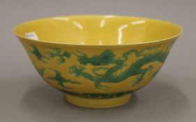 A Chinese yellow ground porcelain bowl decorated with five-clawed dragons chasing a flaming pearl.