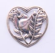 A silver brooch in the form of a bird within a heart. 3.25 cm high.