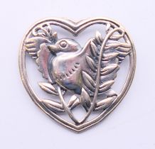 A silver brooch in the form of a bird within a heart. 3.25 cm high.