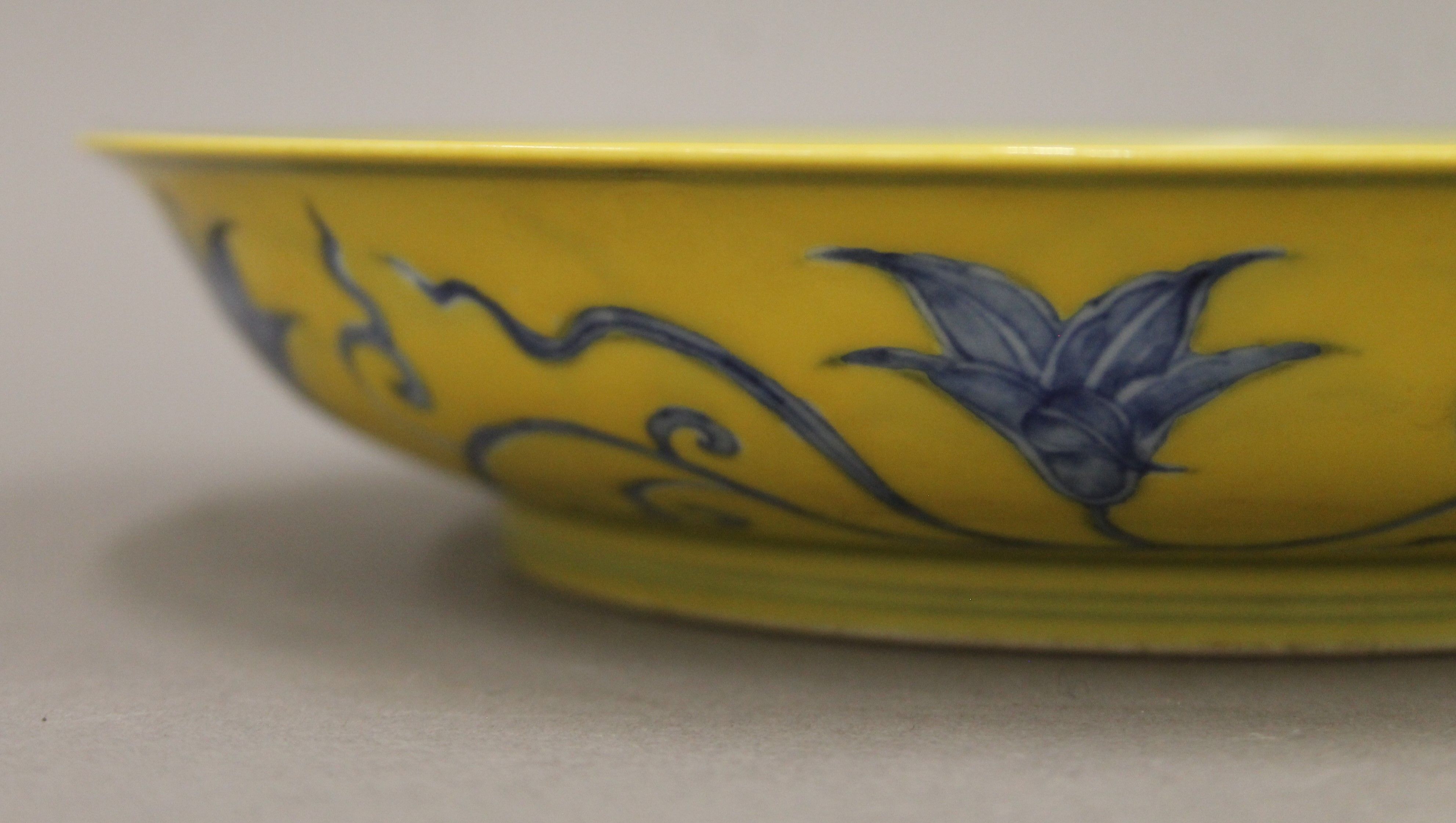 A Chinese yellow ground porcelain dish decorated with blue trailing foliage. 20.5 cm diameter. - Image 3 of 4