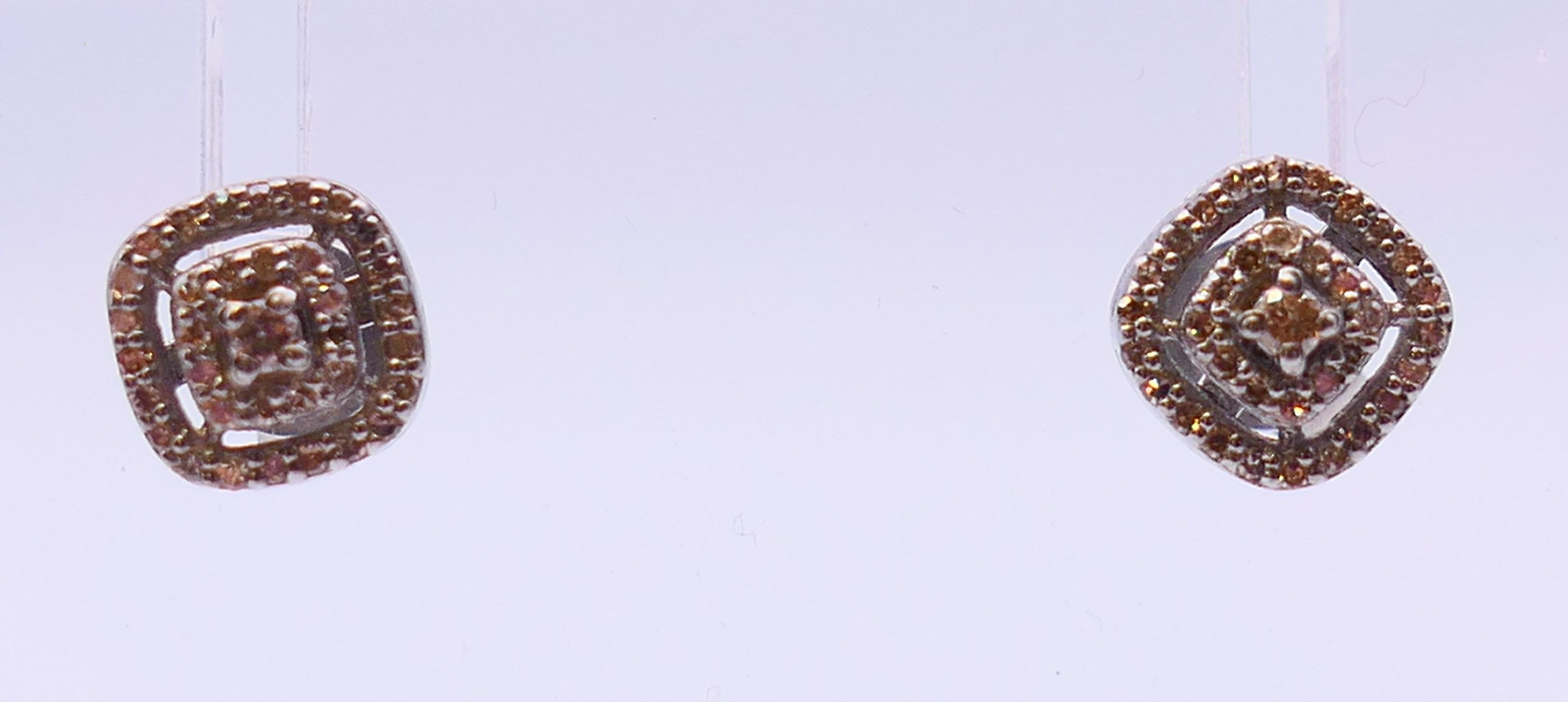 A pair of silver and diamond stud earrings. 0.75 cm diameter.