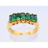 An 18 K gold emerald seven-stone row ring. Ring size O.