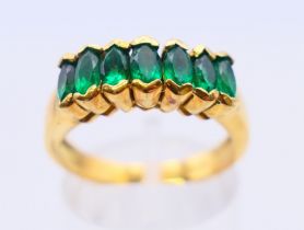 An 18 K gold emerald seven-stone row ring. Ring size O.