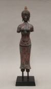A Far Eastern model of a female deity on a stand. 45.5 cm high overall.