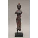 A Far Eastern model of a female deity on a stand. 45.5 cm high overall.