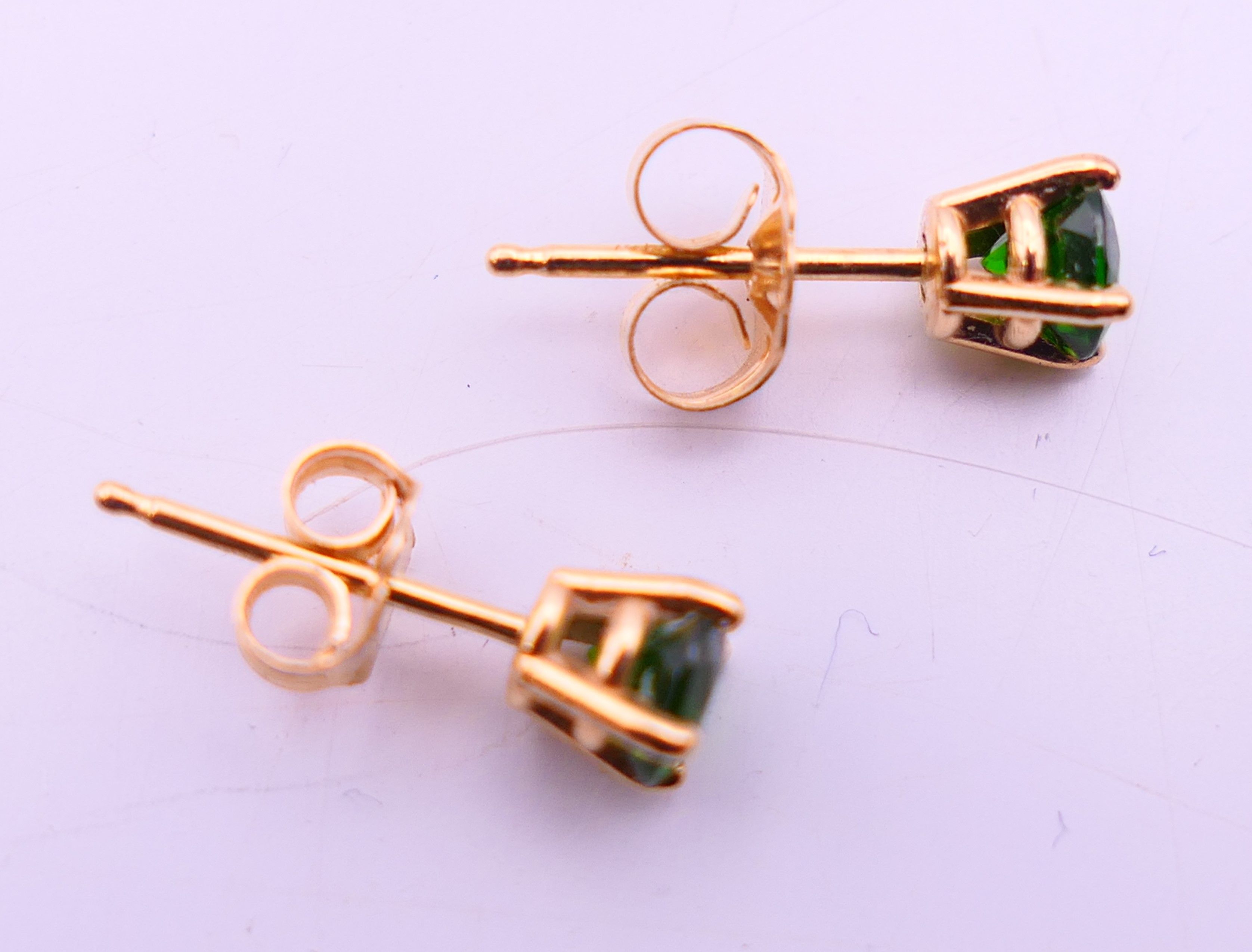 A pair of 14 k gold earrings set with green gemstones, possibly emeralds. 0.5 cm diameter. - Image 4 of 6