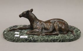 A large patinated bronze model of a fawn mounted on a variegated green marble base. 43 cm long.