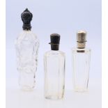 Three silver topped scent bottles. Largest 12.5 cm high.
