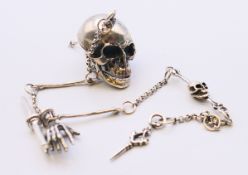 A silver watch chain with skull and hand fobs. Chain 28 cm long.