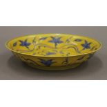 A Chinese yellow ground porcelain dish decorated with blue trailing foliage. 20.5 cm diameter.